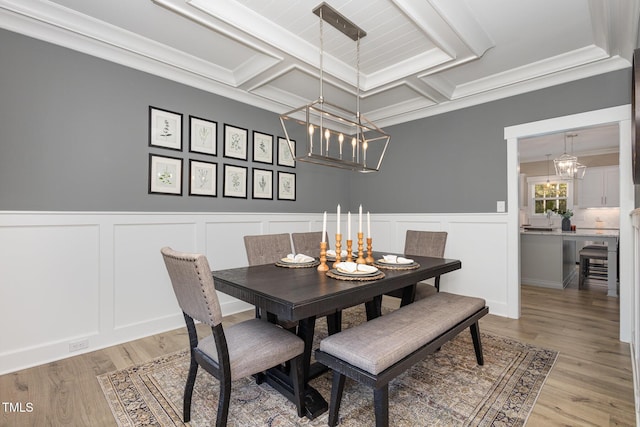 dining room featuring coffered ceiling, ornamental molding, a chandelier, and light wood-type flooring