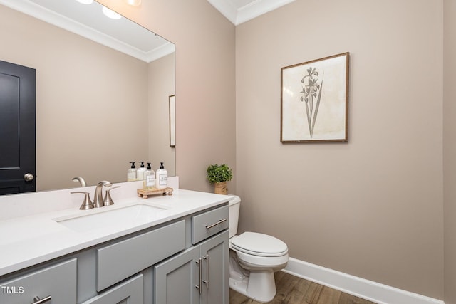 bathroom featuring vanity, hardwood / wood-style floors, ornamental molding, and toilet