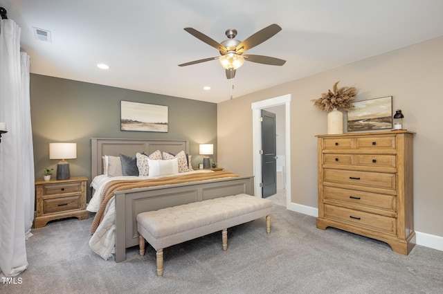 bedroom featuring light carpet, ensuite bath, and ceiling fan