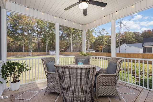 sunroom / solarium featuring rail lighting and ceiling fan