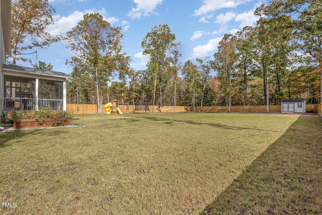 view of yard featuring a storage shed, a playground, and a sunroom