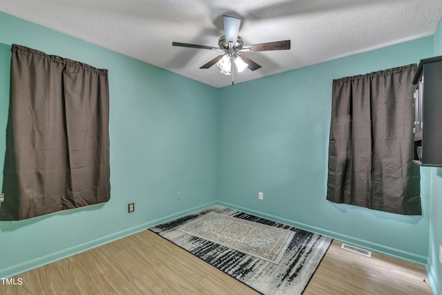 empty room with wood-type flooring, a textured ceiling, and ceiling fan