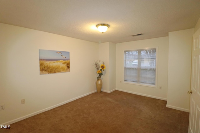 empty room featuring dark carpet and a textured ceiling