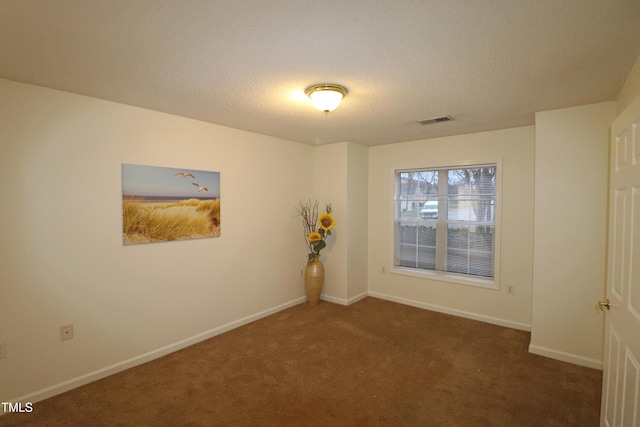 carpeted empty room featuring a textured ceiling