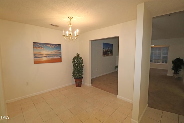 unfurnished room with light tile patterned floors, a chandelier, and a textured ceiling