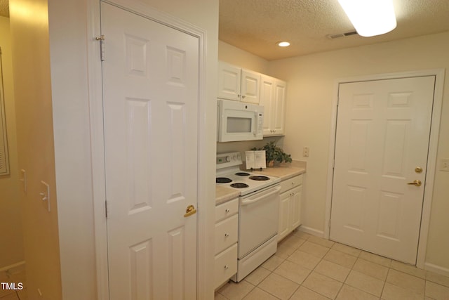 kitchen with light tile patterned floors, white appliances, and white cabinetry