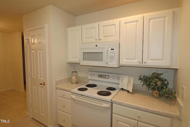 kitchen featuring light tile patterned floors, white appliances, and white cabinetry