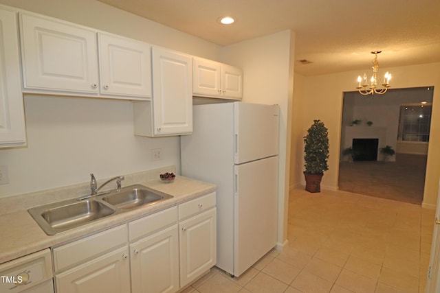 kitchen featuring white cabinetry, sink, white refrigerator, decorative light fixtures, and light tile patterned flooring