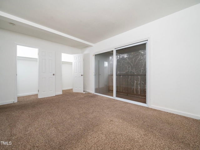 empty room with beam ceiling and carpet flooring