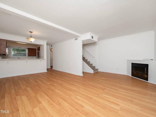 unfurnished living room featuring ornamental molding and light hardwood / wood-style flooring