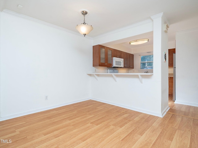 kitchen featuring a breakfast bar, hanging light fixtures, ornamental molding, light hardwood / wood-style floors, and kitchen peninsula