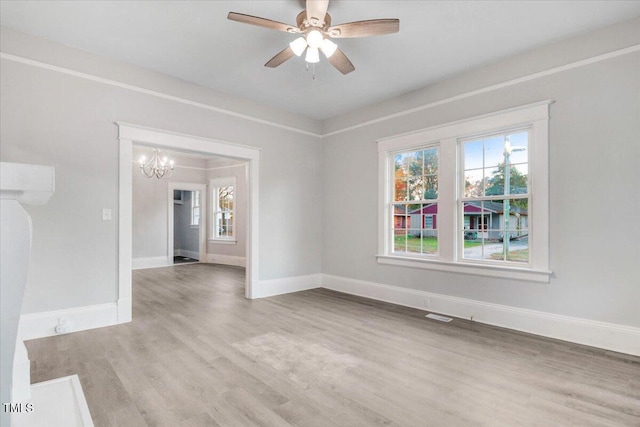 spare room with ceiling fan with notable chandelier and light wood-type flooring