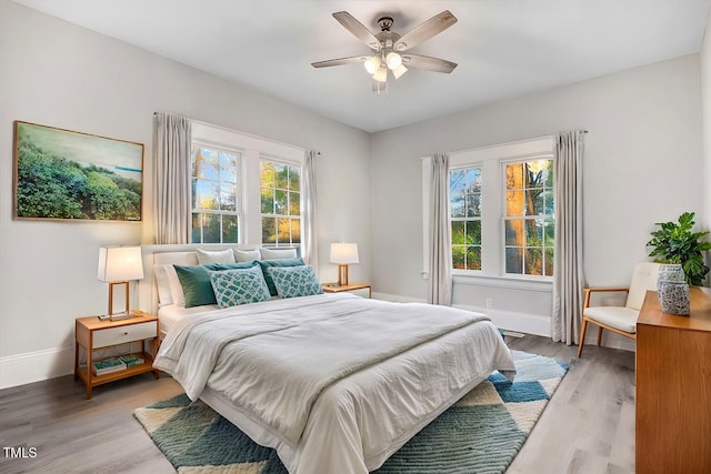 bedroom with light hardwood / wood-style floors, multiple windows, and ceiling fan