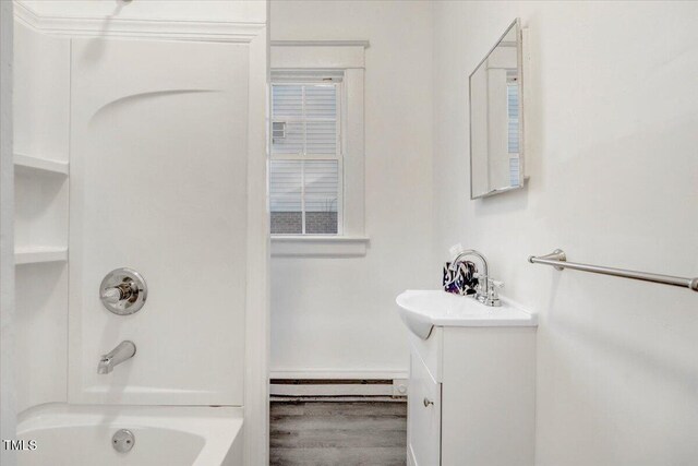 bathroom with shower / tub combination, vanity, hardwood / wood-style flooring, and a baseboard heating unit