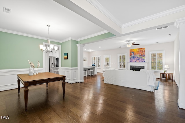 dining area with ceiling fan with notable chandelier, ornamental molding, and dark wood-type flooring