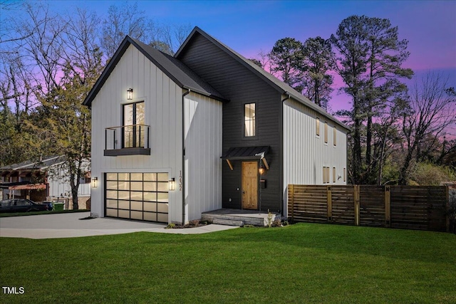 back house at dusk featuring a garage and a lawn