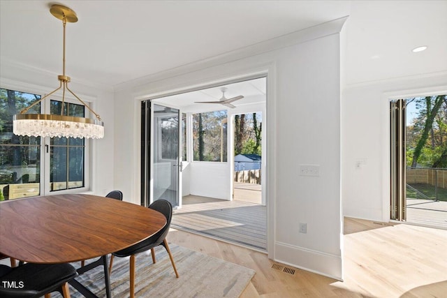 dining area featuring crown molding, a notable chandelier, and light hardwood / wood-style floors