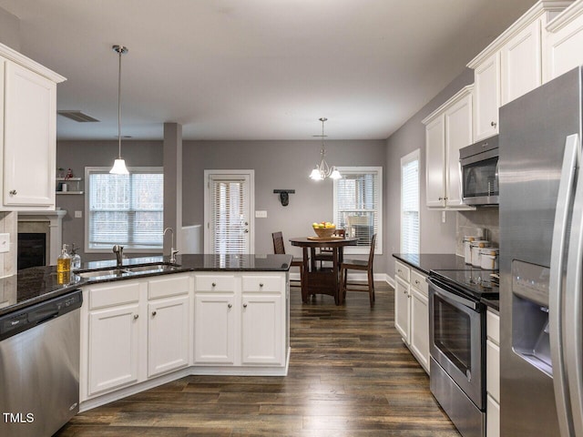 kitchen with a wealth of natural light, stainless steel appliances, and hanging light fixtures