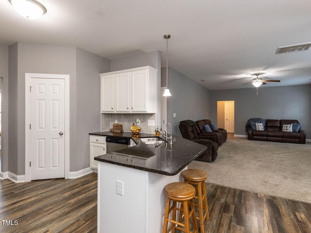 kitchen featuring white cabinets, decorative light fixtures, dark wood-type flooring, and dishwasher