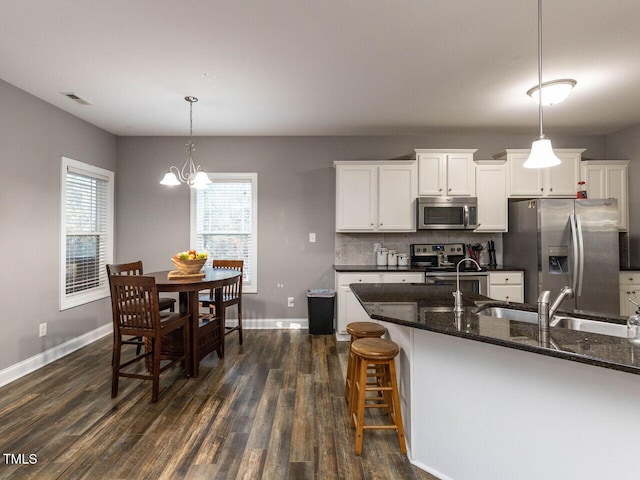 kitchen with white cabinets, decorative light fixtures, dark hardwood / wood-style flooring, and stainless steel appliances