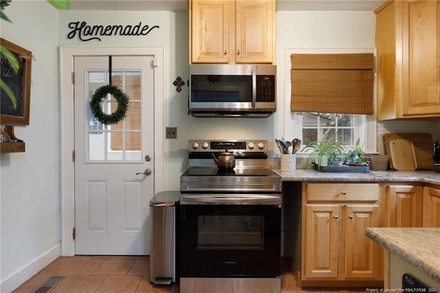 kitchen with light brown cabinetry, light tile patterned floors, and stainless steel appliances