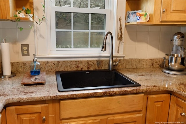 kitchen featuring backsplash, light stone counters, and sink