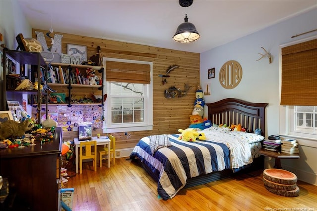 bedroom with hardwood / wood-style flooring, multiple windows, and wood walls