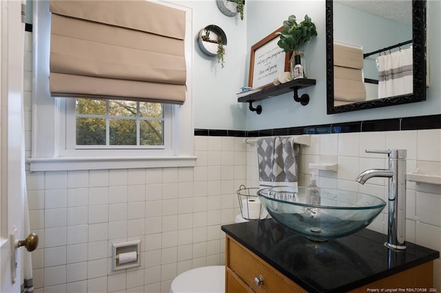 bathroom with vanity, toilet, and tile walls