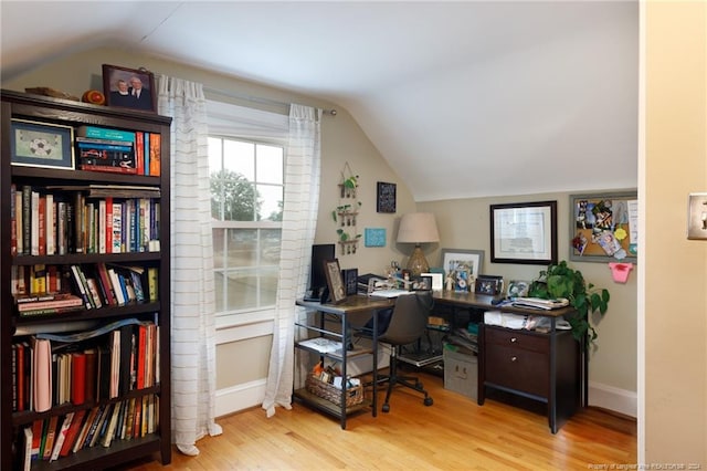 home office with light hardwood / wood-style flooring and lofted ceiling