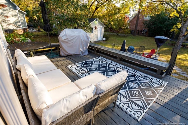 wooden deck with an outdoor living space, a yard, area for grilling, and a storage shed