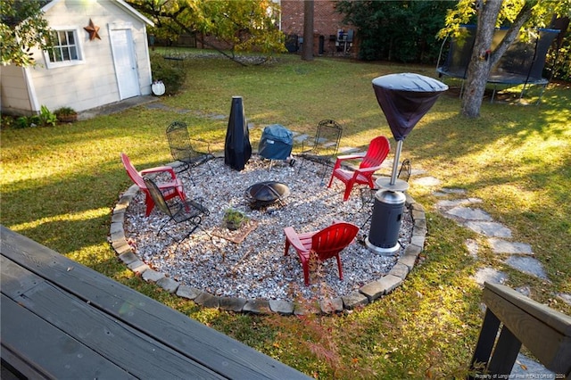 view of yard with a storage shed, a trampoline, and an outdoor fire pit