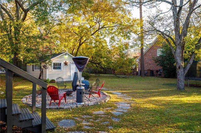 view of yard featuring a fire pit and a trampoline