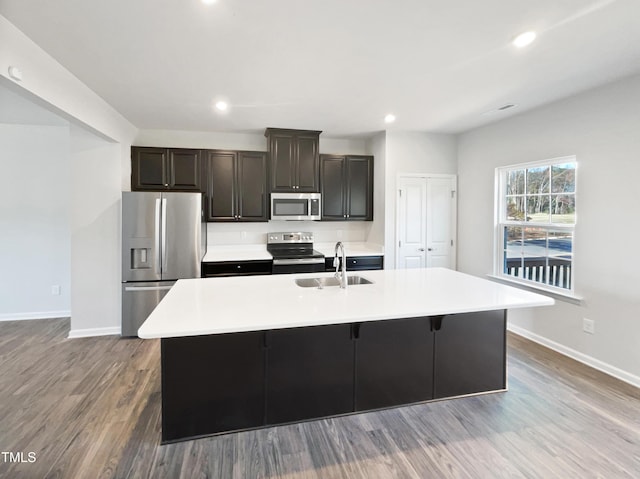 kitchen with appliances with stainless steel finishes, a center island with sink, light hardwood / wood-style floors, and sink