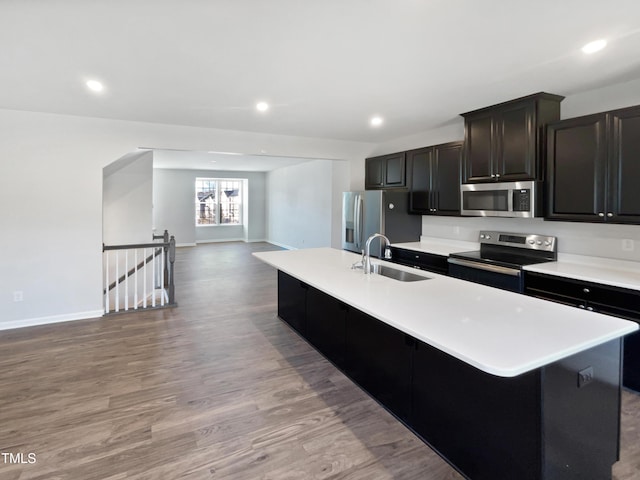 kitchen featuring a breakfast bar, a kitchen island with sink, sink, light hardwood / wood-style flooring, and appliances with stainless steel finishes