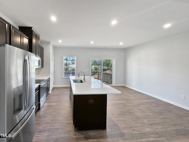 kitchen with sink, dark hardwood / wood-style flooring, stainless steel appliances, and an island with sink