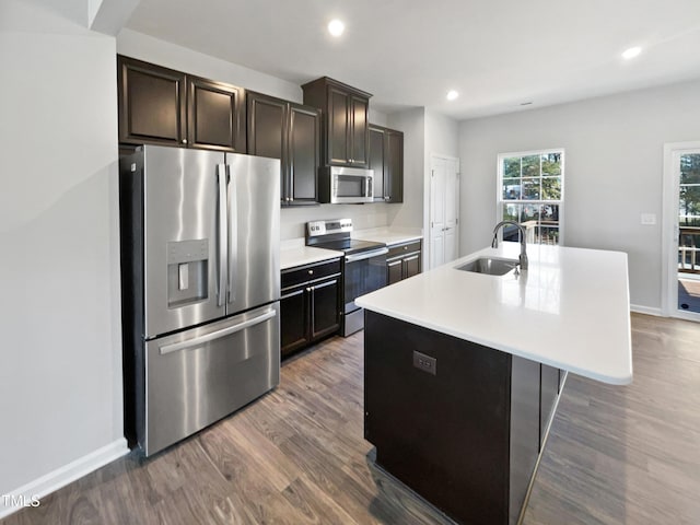 kitchen featuring dark brown cabinetry, sink, stainless steel appliances, dark hardwood / wood-style flooring, and a kitchen island with sink