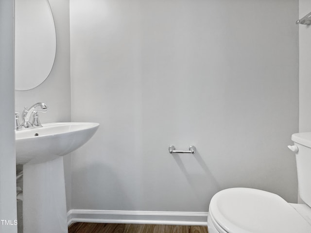 bathroom with wood-type flooring, toilet, and sink