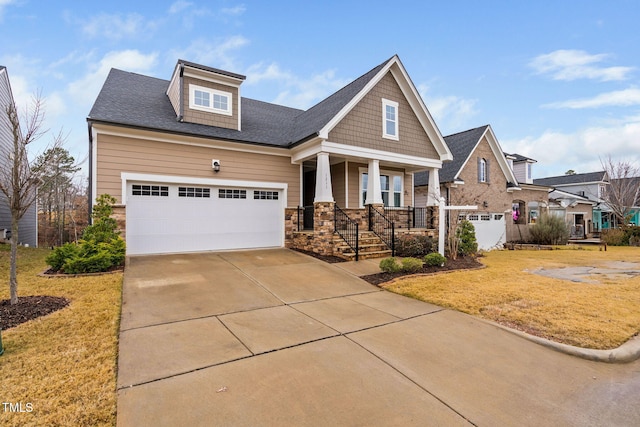 craftsman-style home featuring covered porch, a front yard, and a garage