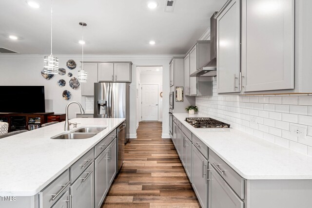 kitchen featuring stainless steel appliances, a kitchen island with sink, dark wood-type flooring, sink, and decorative light fixtures