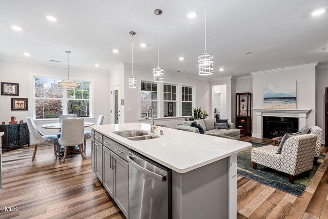 kitchen with a kitchen island with sink, sink, pendant lighting, dishwasher, and hardwood / wood-style floors