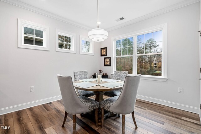 dining area with wood-type flooring, plenty of natural light, and ornamental molding