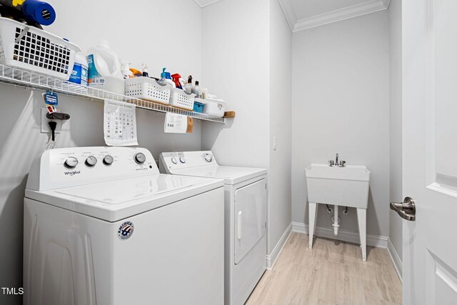 laundry area with light wood-type flooring, separate washer and dryer, and crown molding