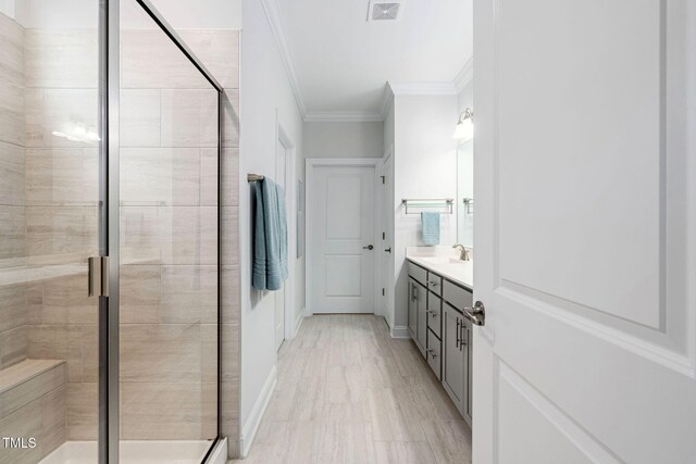 bathroom featuring ornamental molding, vanity, and a shower with shower door