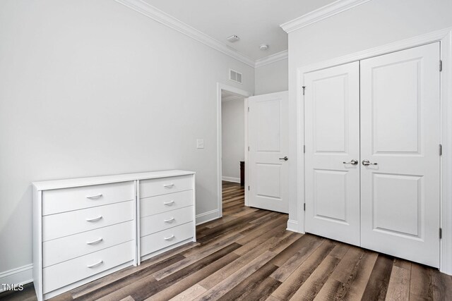 unfurnished bedroom with dark hardwood / wood-style flooring, a closet, and ornamental molding