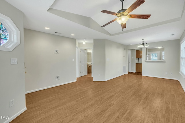 unfurnished living room featuring ceiling fan with notable chandelier, lofted ceiling, and light hardwood / wood-style flooring