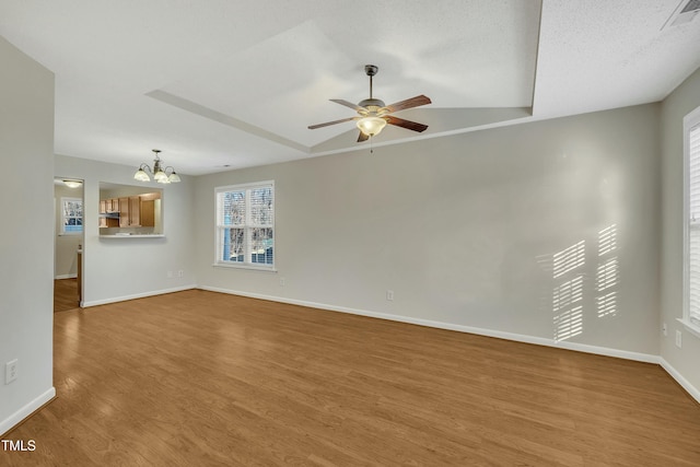 unfurnished living room with a textured ceiling, ceiling fan with notable chandelier, hardwood / wood-style flooring, and vaulted ceiling