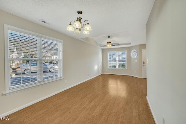 empty room with wood-type flooring, ceiling fan with notable chandelier, and a textured ceiling