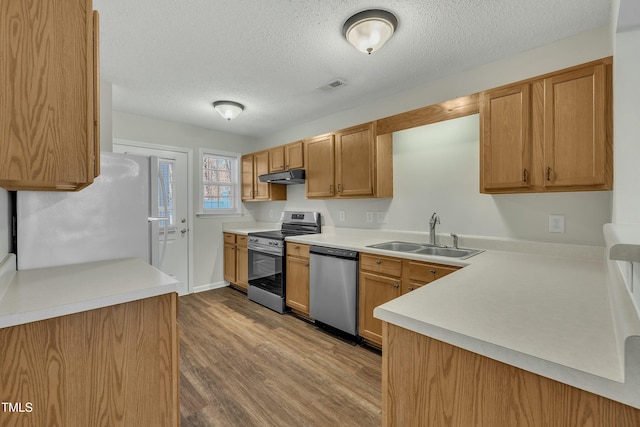 kitchen with a textured ceiling, sink, stainless steel appliances, and light hardwood / wood-style flooring