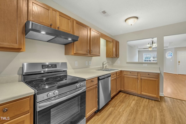 kitchen featuring appliances with stainless steel finishes, a textured ceiling, ceiling fan, sink, and light hardwood / wood-style floors