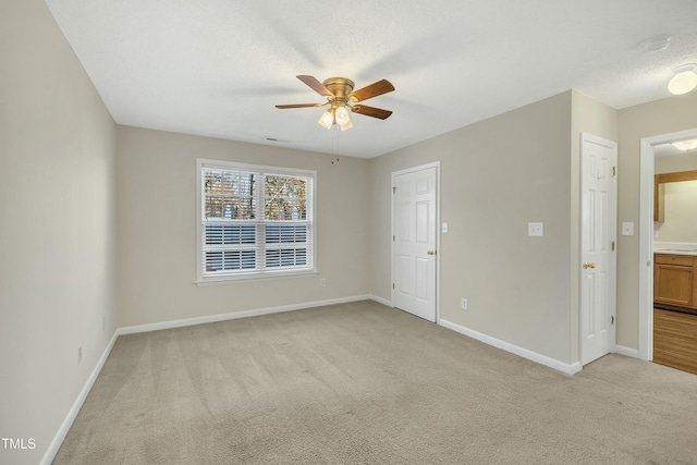 spare room with a textured ceiling, ceiling fan, and light carpet